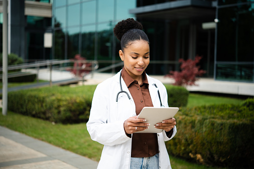 Portrait of a young female doctor on a break walking and using a digital tablet