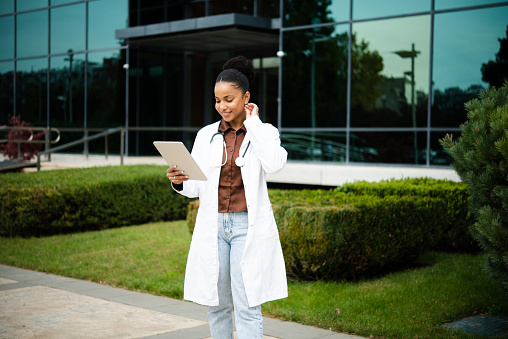 Portrait of a young female doctor on a break walking and using a digital tablet