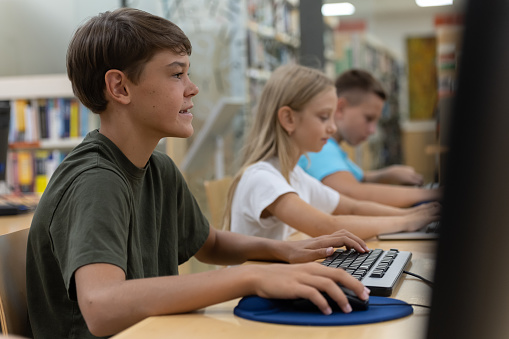 Children browse computers and talk.
