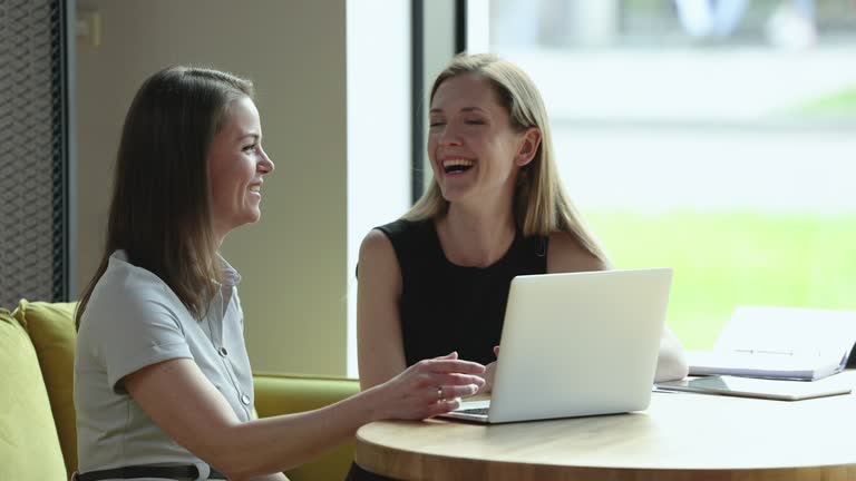 Two cheerful office friends women meeting in office lounge cafe