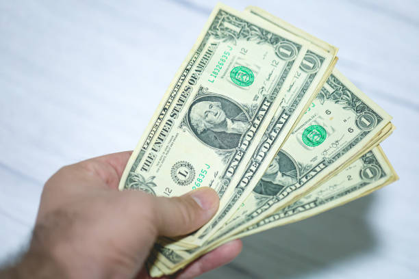 istock A man holding US one dollar bills. Close-up Photo. 1483705246