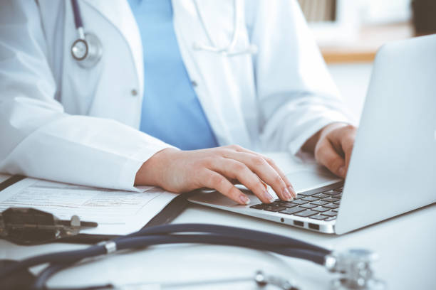 istock Unknown woman-doctor typing on laptop computer while sitting at the table. Medicine concept 1483706771