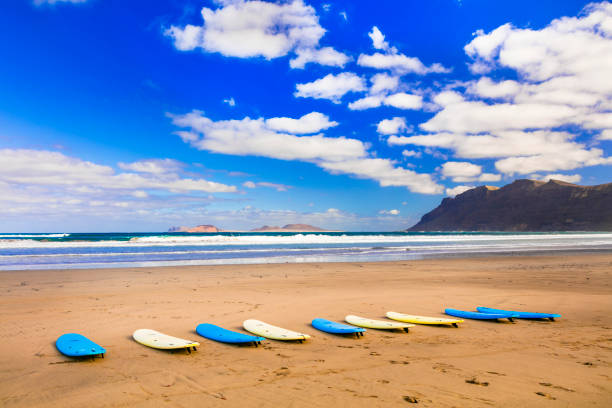 surfbretter am breiten sandstrand famara - berühmter strand zum surfen auf lanzarote, kanarische inseln - famara stock-fotos und bilder