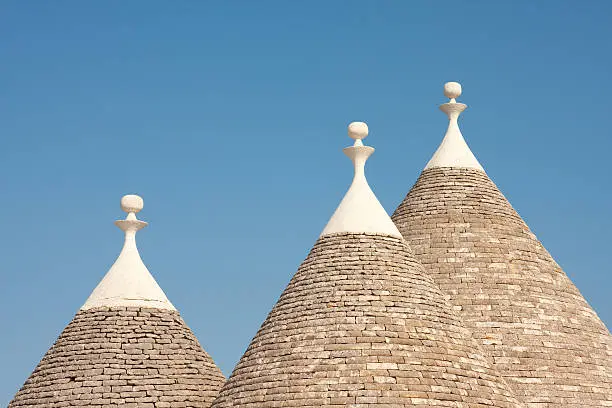 Image of the cone shaped roof's of traditional Trulli houses in the Puglia region of Italy.  Image shot against the blue summer sky.