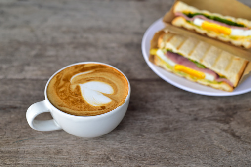 top view coffee cup and sandwich on old wood table and copy space. selective focus. light breakfast food concept.