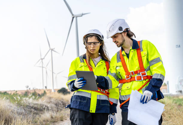 istock Two engineers caucasian man and woman in hardhat and goggles talk about system installation and walking to verify that a wind turbine is running correctly and effectively, Renewable energy 1483727348