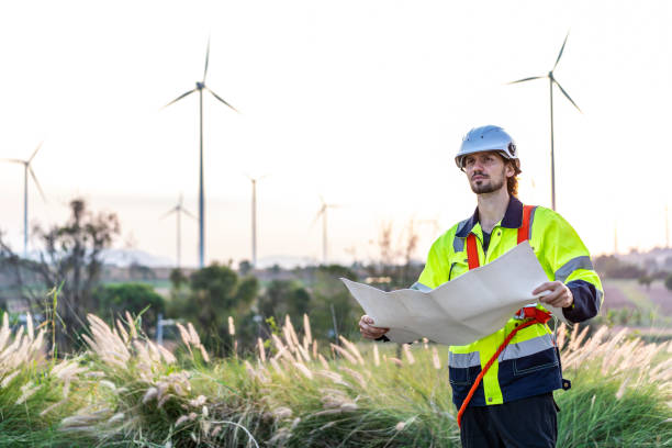 istock Caucasian engineer man in uniform wearing helmet, viewing data on blueprint and stay in front of row of windmill or wind turbine, wind turbine generate electricity, Environmentally friendly 1483727413