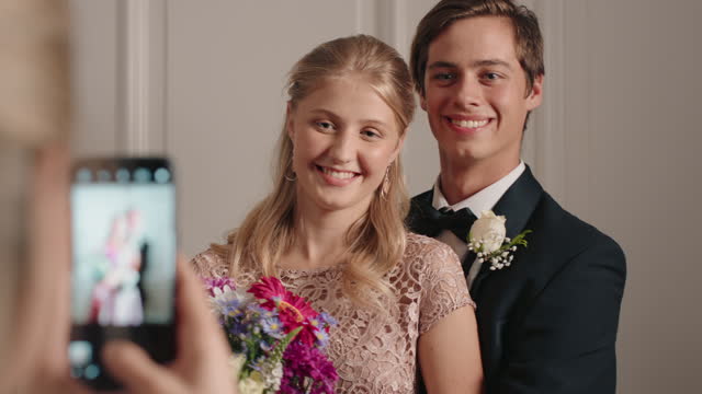 teenage couple prom night teens posing for photo with proud mom photographing teenagers for homecoming dance wearing stylish fashion excited for glamourous event 4k