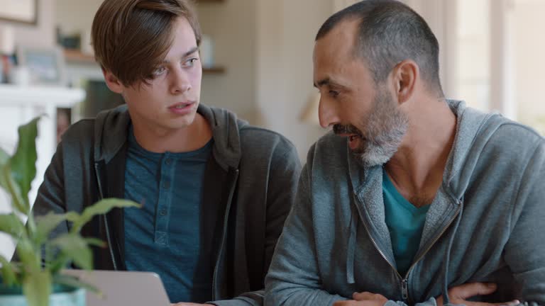 father and son using laptop computer dad helping teenage boy with homework at home teaching problem solving parent supporting education 4k