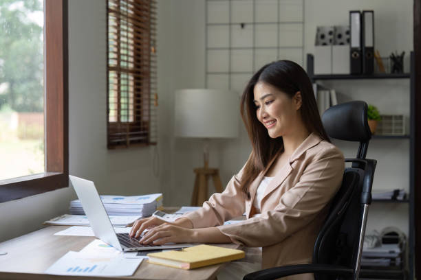 istock Young Happy Businesswoman Using Computer in Modern Office with Colleagues 1483733175