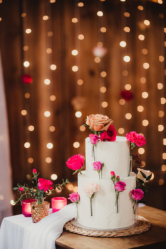 Two tiered wedding cake with roses and string lights