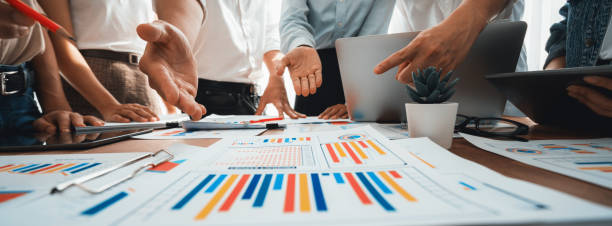 istock Focus financial report papers with blurred analyst team working. Scrutinize 1483743730