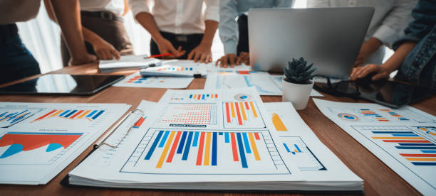 istock Focus financial report papers with blurred analyst team working. Scrutinize 1483743847