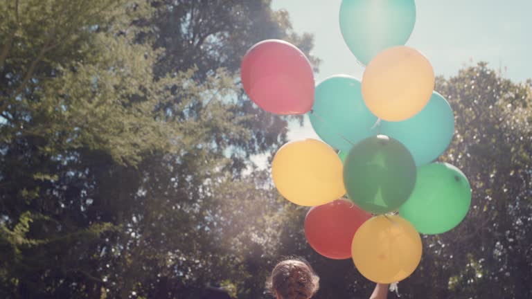 happy little girl running with balloons in park celebrating birthday party having fun summer day feeling excited playfully enjoying childhood freedom outdoors 4k