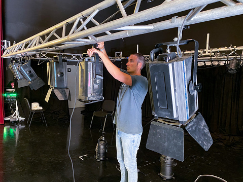 Sound technician working on the assembly of spotlights on a stage