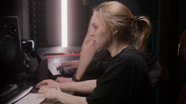 istock Female sound engineer uses mixing console, creates song with producer 1483752341