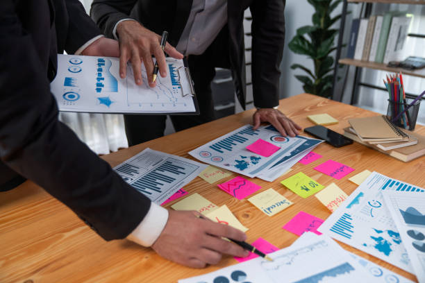istock Busy analyst team discuss financial data on dashboard with post note. Fervent 1483753925