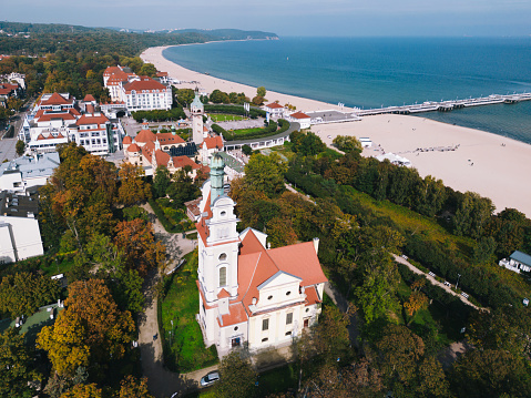 Sopot, Poland - September 29, 2017: Sopot resort with SPA, old lighthouse, wooden pier (molo), marina, yachts,  beach, hotels, square, vacation infrastructure and park. Aerial view at sunrise.