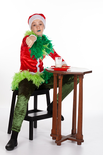 Full portrait of young girl wearing red santa clause hat like grinch fist pump, isolated on white background. Concept for cool grinch interacting