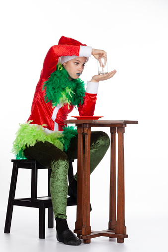 Full portrait of young girl wearing red santa clause hat like grinch question look with empty milk, isolated on white background. Human emotion facial expression