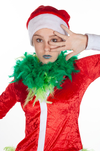 Closeup portrait of young girl wearing red santa clause hat, grinch hand to face with eyes open no expression, isolated on white background. Neutral human emotion facial expression