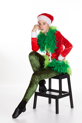 Grinch hand on hip and in deep disbelief pose, grumpy greedy miserly young girl wearing red santa clause hat, isolated on white background. Negative human emotion facial expression