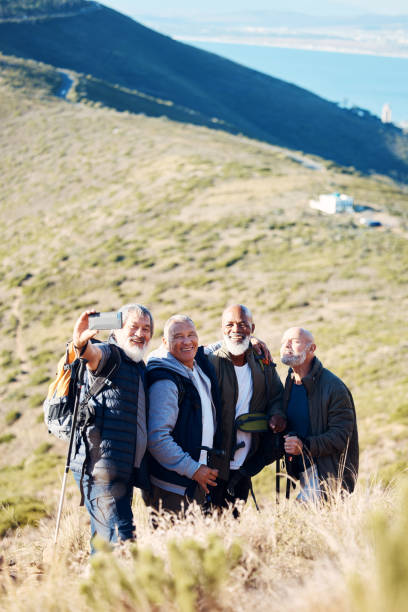 青のフィールド背景に高齢者、男性、ハイキングの自撮り写真、幸せでリラックス、陽気で笑顔。高齢者、友人、男性ハイカーグループは、写真、写真、退職活動の記憶で絆を深める - africa senior adult friendship men ストックフォトと画像