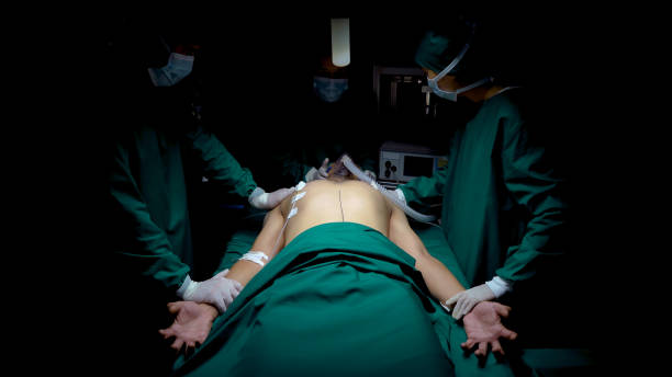 istock Close up, patients lying on bed awaiting surgery in operating room, have convulsions stiff hands, nose and mouth wearing an oxygen mask, three doctors rushed over to see patient closely. 1483768768