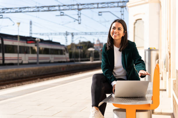 donna latina freelance aspetta alla stazione seduta su una panchina per finire alcuni compiti di lavoro - getting the mail foto e immagini stock