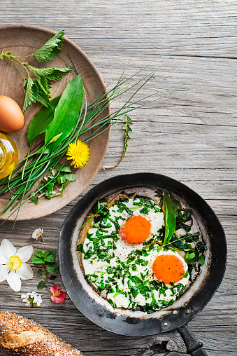 Fried eggs with fresh spring plants and herbs. Healthy spring food concept.