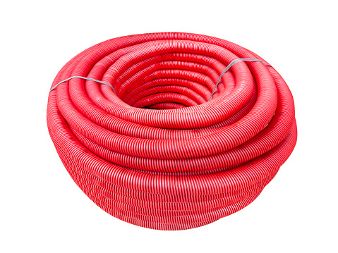 HDPE corrugated pipe isolated on white background. Protection underground cable. Rolled up red corrugated PVC pipe. Red building pipes. Coated corrugated construction pipe.