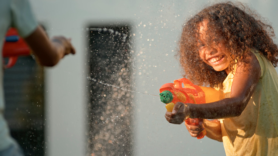 Smiling girl playing with water gun during sunset.