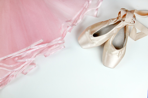 Pointe shoes and a pink ballerina skirt on a white background.