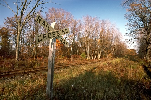 Autumn railway crossing sign scenery with impressive shadows