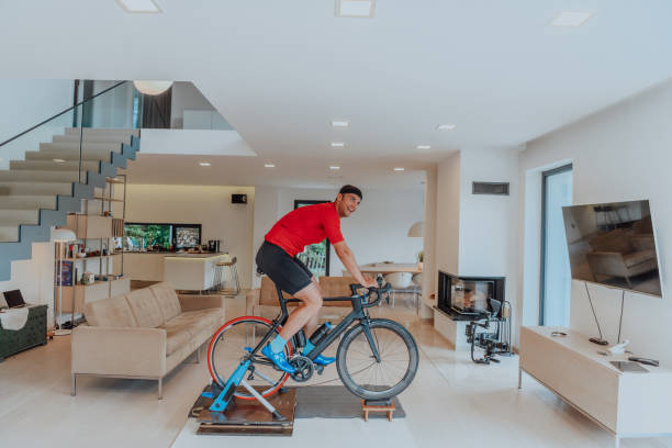 istock A man riding a triathlon bike on a machine simulation in a modern living room. Training during pandemic conditions. 1483776428