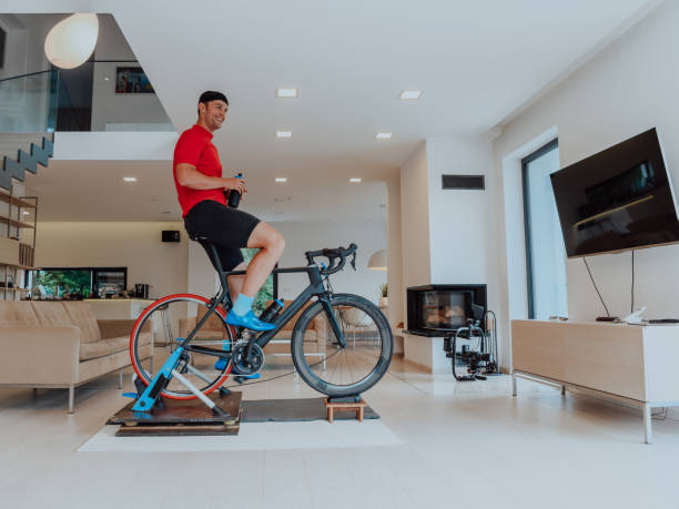 istock A man riding a triathlon bike on a machine simulation in a modern living room. Training during pandemic conditions. 1483776523