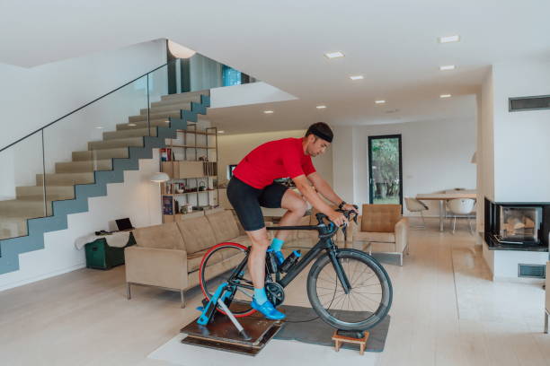 istock A man riding a triathlon bike on a machine simulation in a modern living room. Training during pandemic conditions. 1483776783