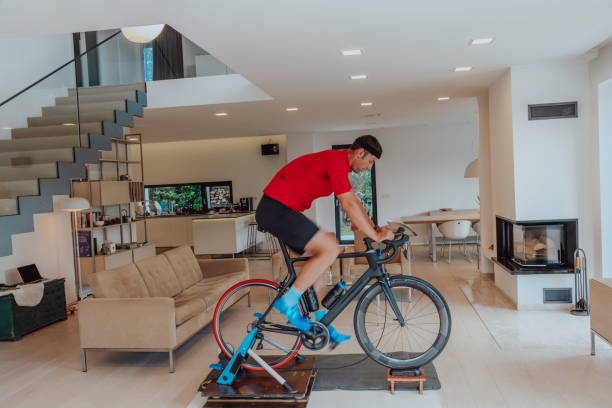 istock A man riding a triathlon bike on a machine simulation in a modern living room. Training during pandemic conditions. 1483777066