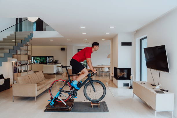 istock A man riding a triathlon bike on a machine simulation in a modern living room. Training during pandemic conditions. 1483778311