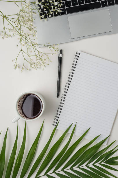 istock Flat lay, top view office table desk. Workspace with blank notebook, office supplies, green leaf, and coffee cup on white background. 1483778797