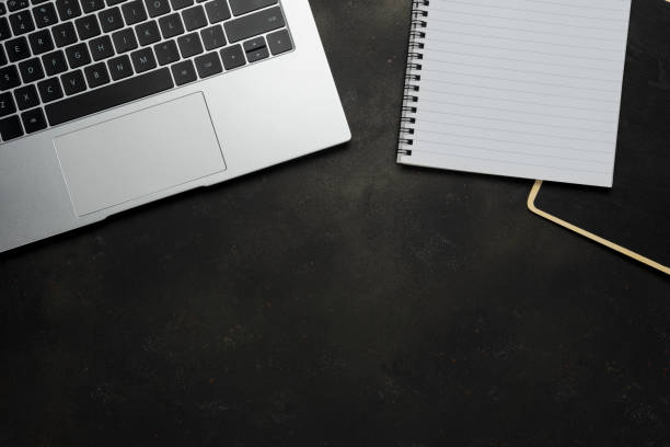 istock Workspace with blank notebook and laptop on black background. Top view with copy space. 1483778812