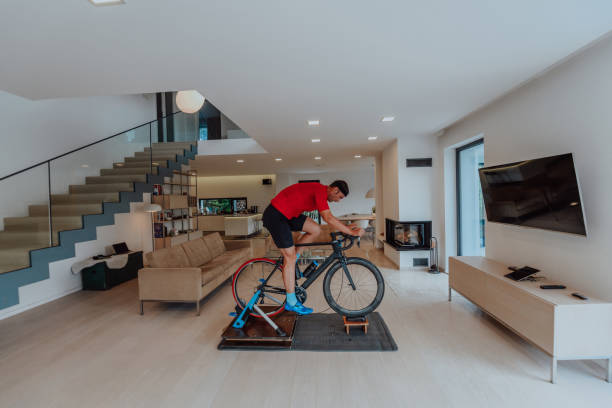 istock A man riding a triathlon bike on a machine simulation in a modern living room. Training during pandemic conditions. 1483778868