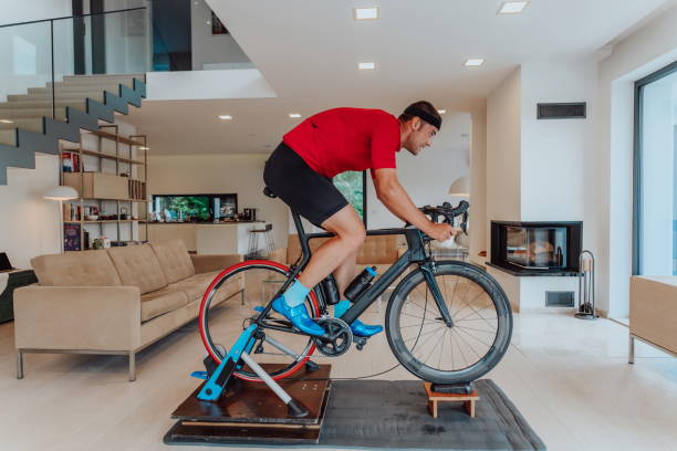 istock A man riding a triathlon bike on a machine simulation in a modern living room. Training during pandemic conditions. 1483780487