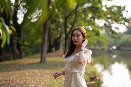 Pretty asian woman wandering and relaxing in a greenery forest park happily.