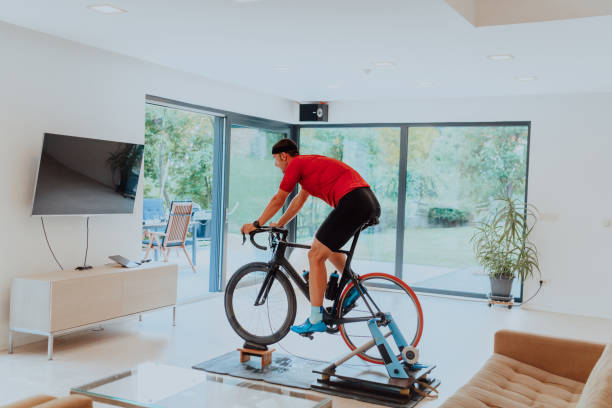 istock A man riding a triathlon bike on a machine simulation in a modern living room. Training during pandemic conditions. 1483785109