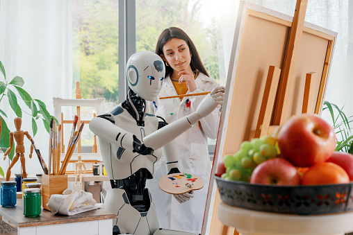 Creative AI robot learning how to paint on canvas in the art studio, a young teacher is training her