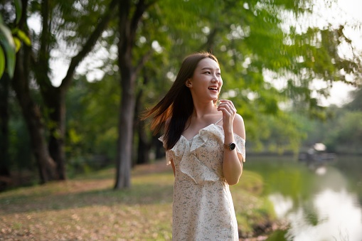 Pretty asian woman wandering and relaxing in a greenery forest park happily.