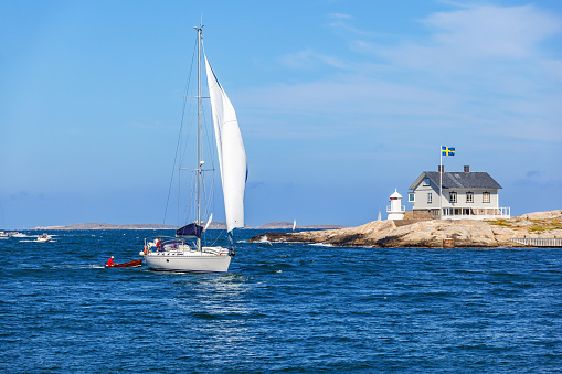 Marstrand, Sweden-July, 2018: Sailboat in a rocky archipelago with a cottage on a cliff