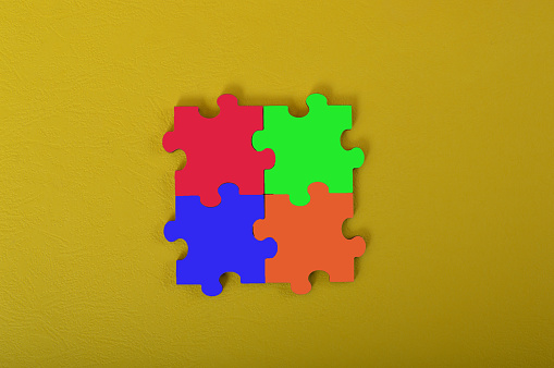 Colorful jigsaw puzzle isolated on a yellow background. Copy space for the text.