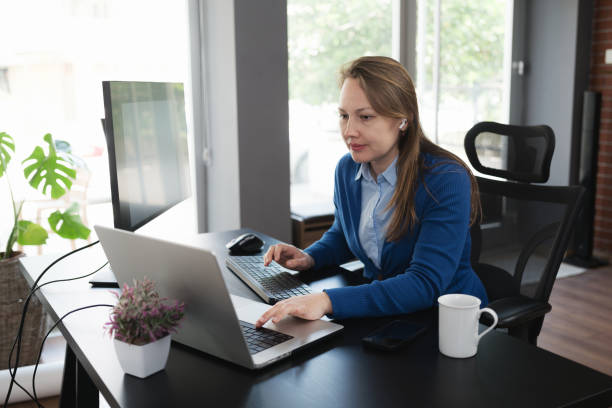 istock Adult Student studying remotely from home using laptop computer and a secondary monitor 1483794157